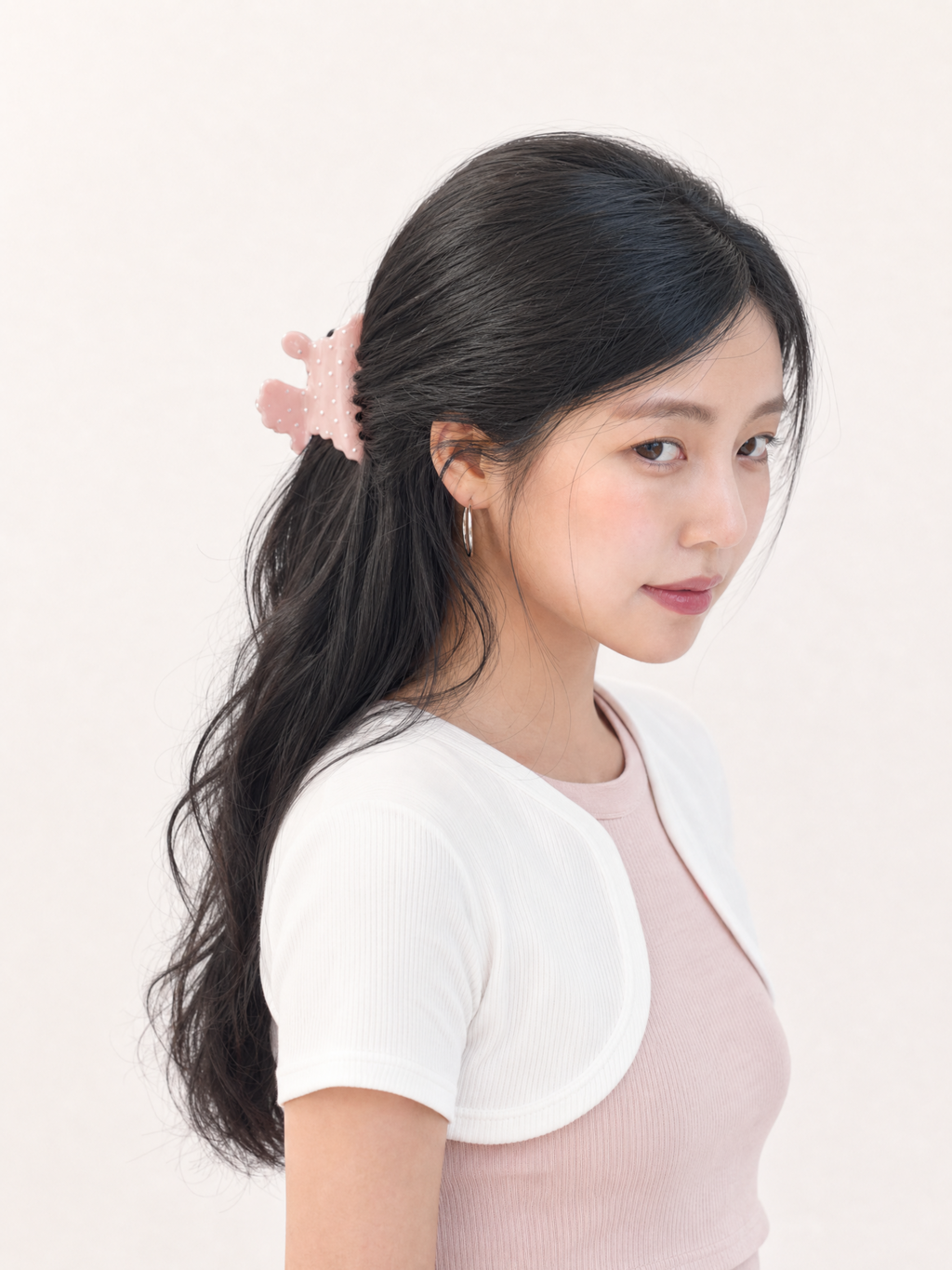Side profile of a Korean model styling a half-up hairstyle using a dusty rose cute puppy polka dot claw clip on wavy hair
