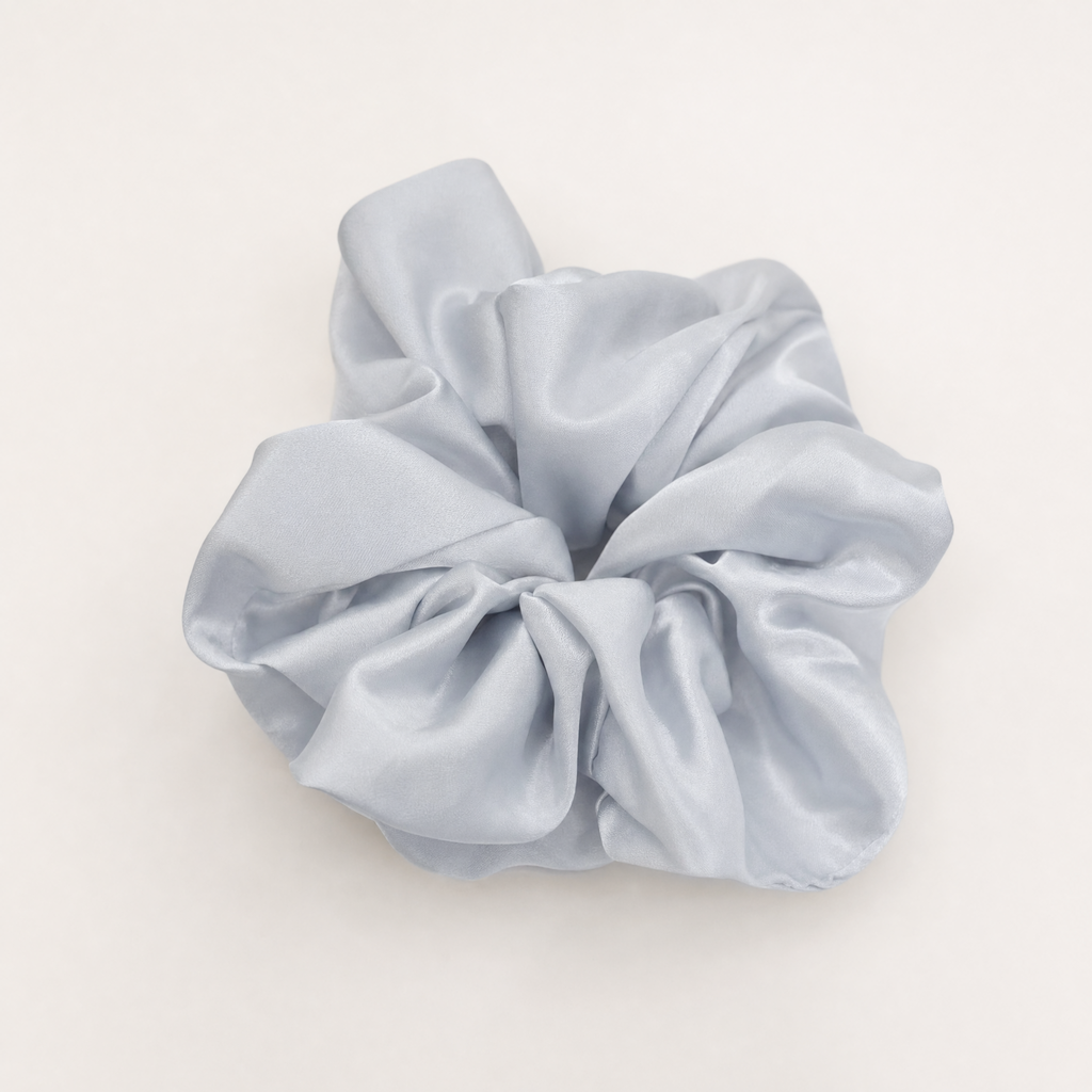 A light blue satin hair scrunchie with a smooth and lustrous texture